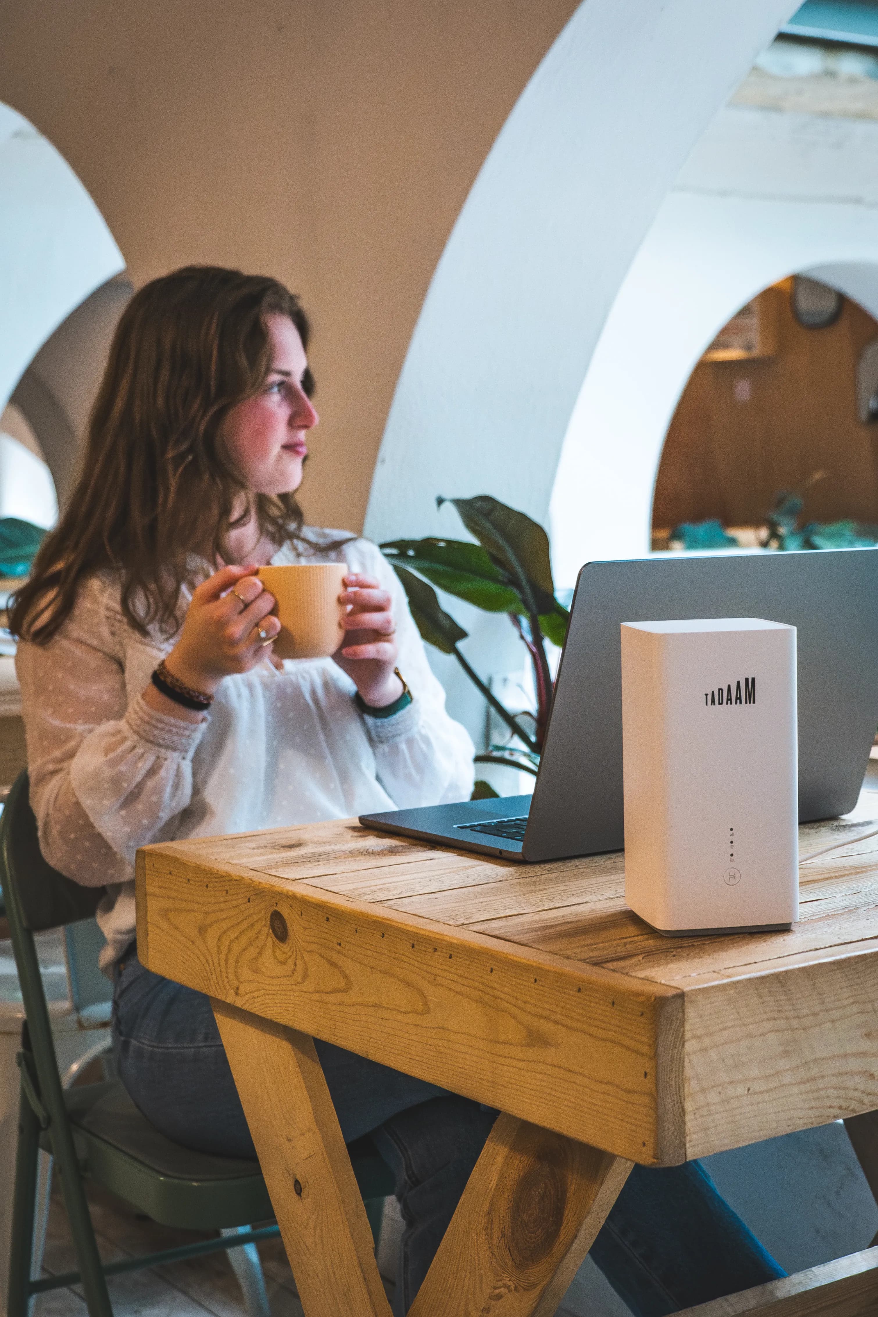 A girl sitting in a cafe, with a laptop and TADAAM modem.