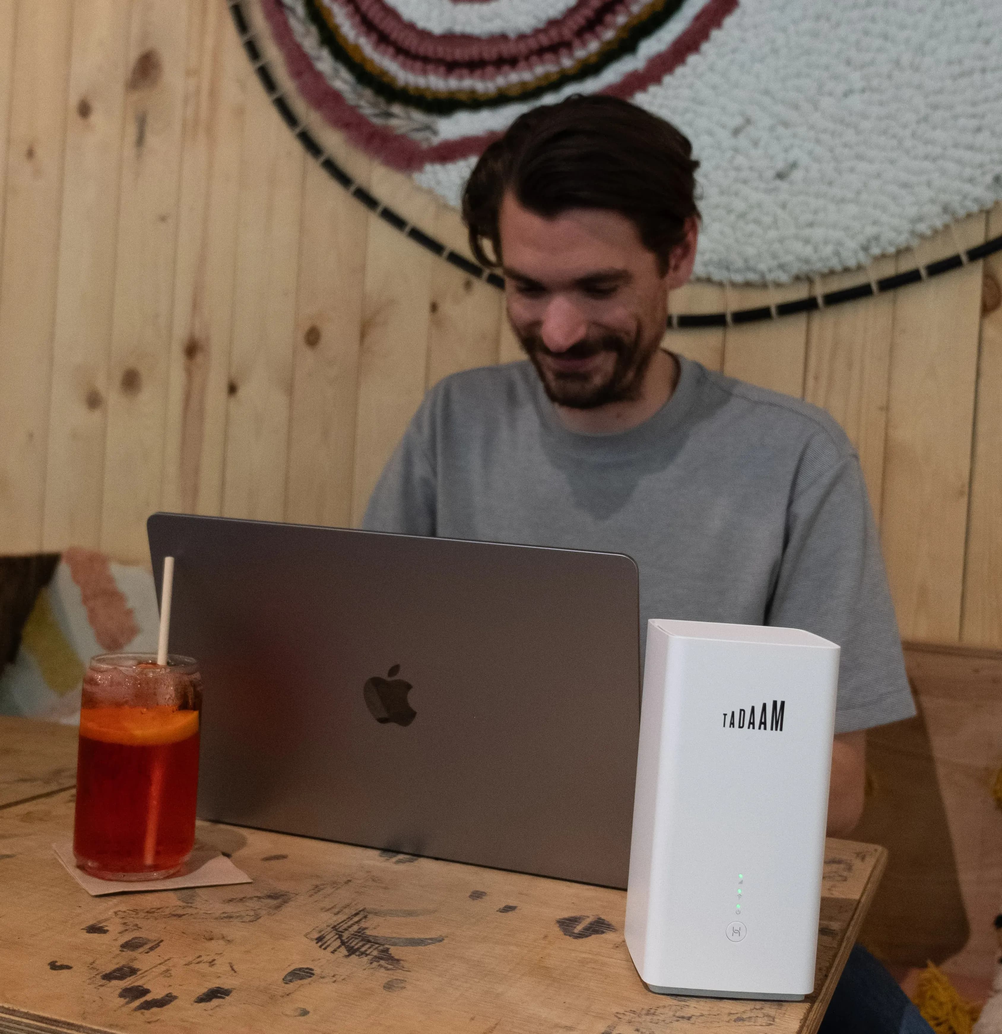 A guy in front of his laptop with TADAAM modem next to it.
