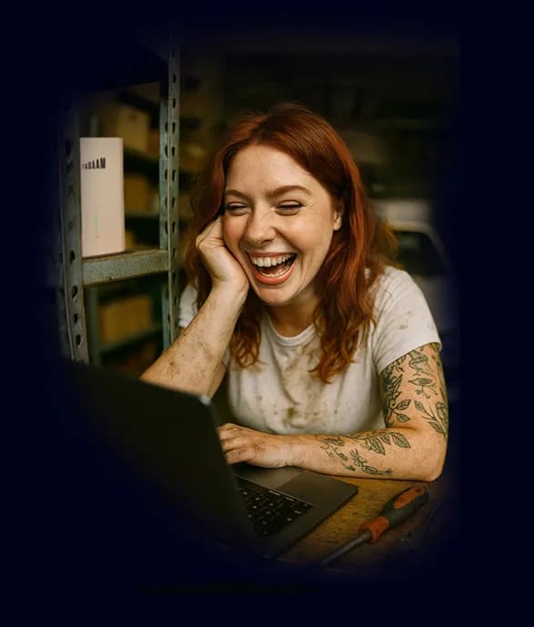 A girl smiling at her laptop screen, the TADAAM modem behind her.