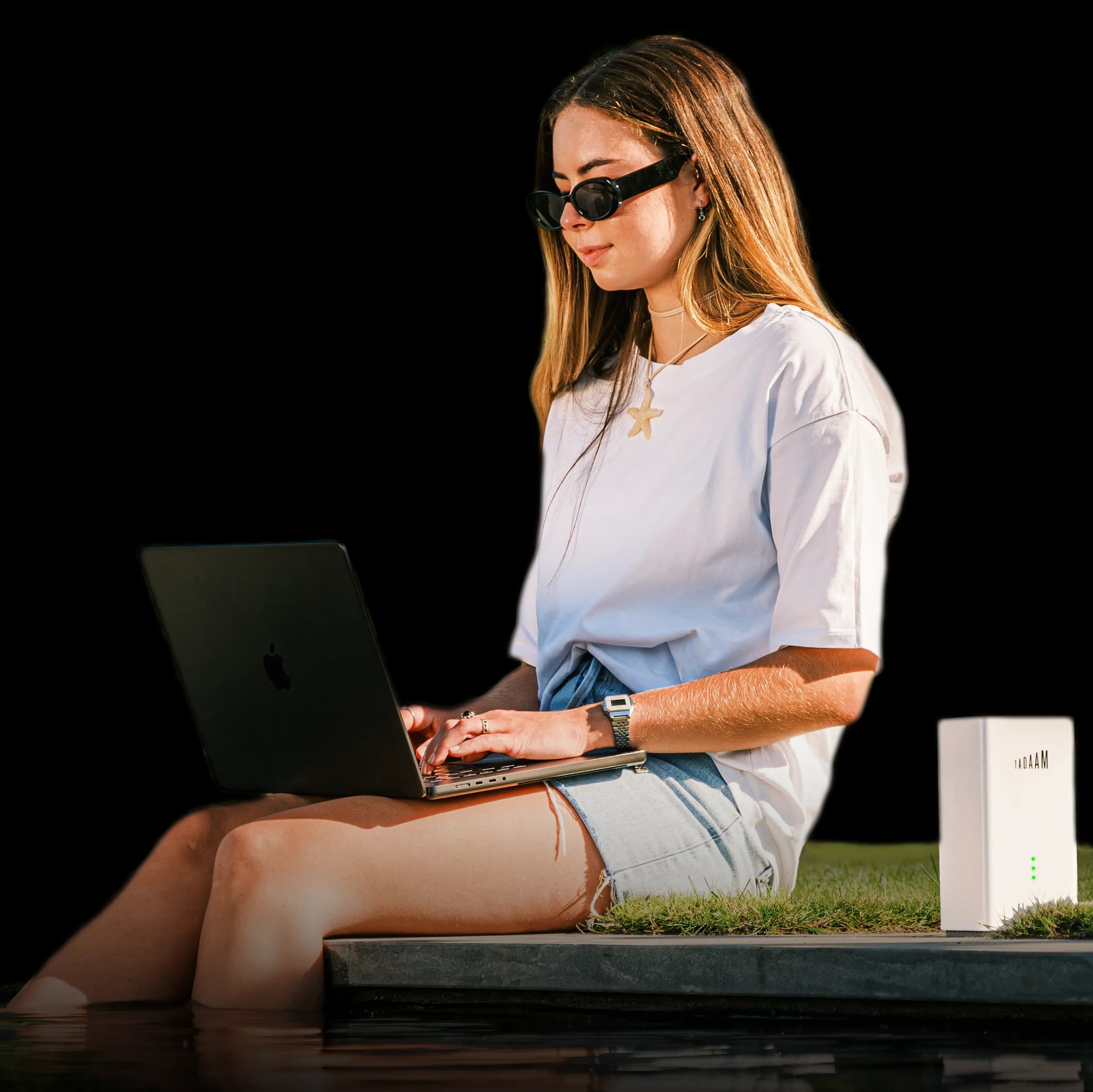 An image of a young woman sitting by the swimming pool with a laptop on her lap and a TADAAM's modem next to her.