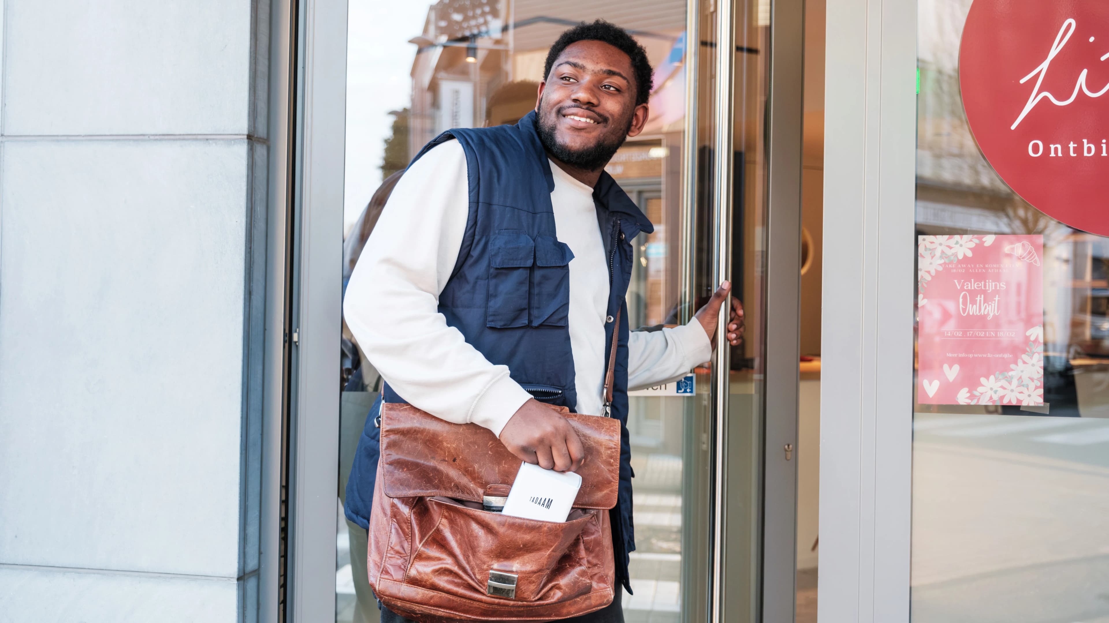 An image of a man walking through the door with a bag and a TADAAM modem sticking out of the bag.