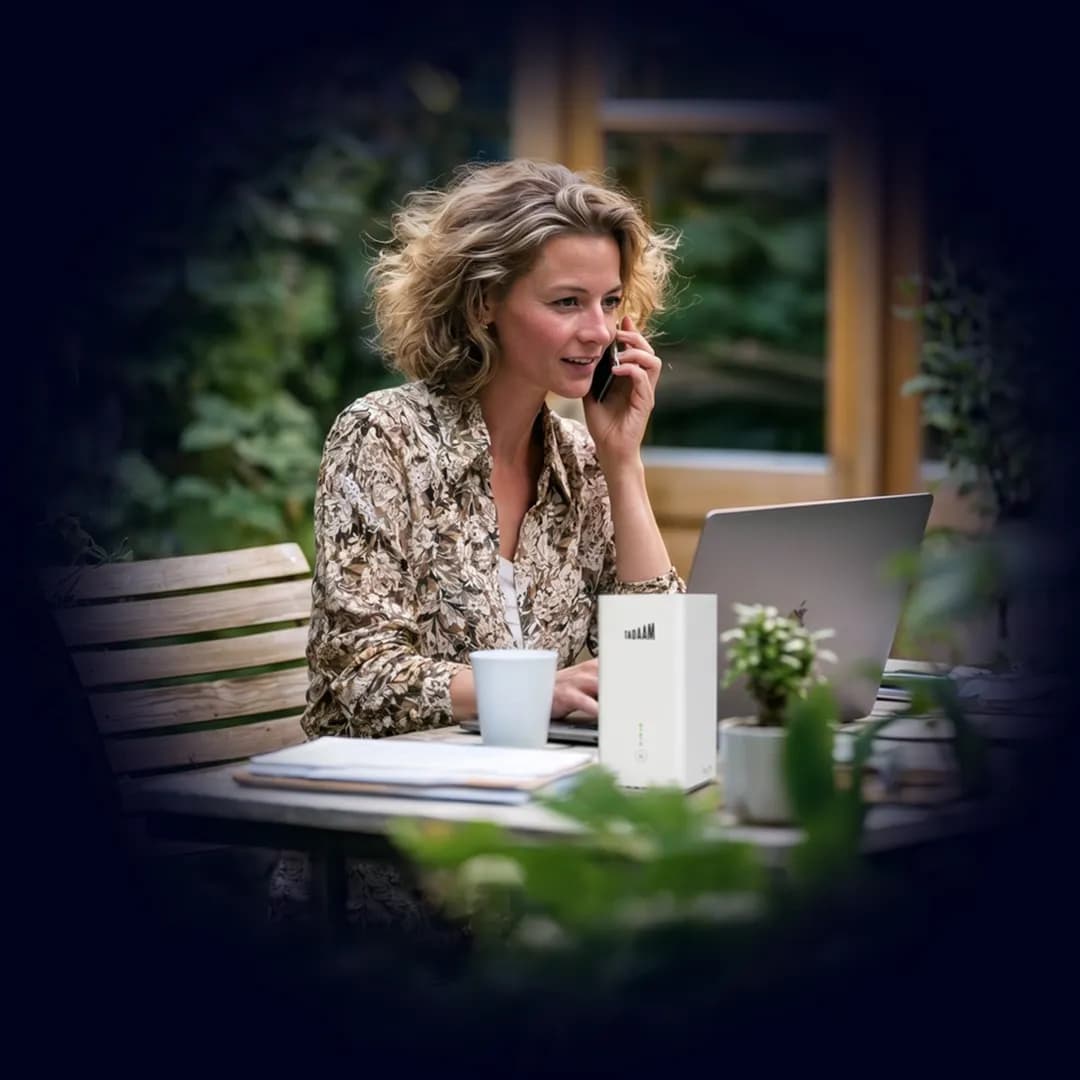 Woman working outside on her laptop, TADAAM modem beside her.