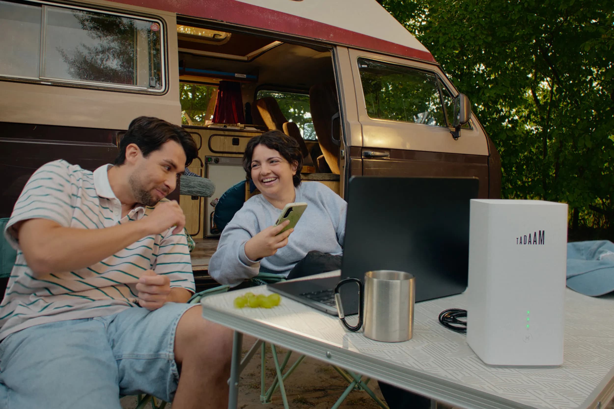 Two people watching a show on their laptop while camping.