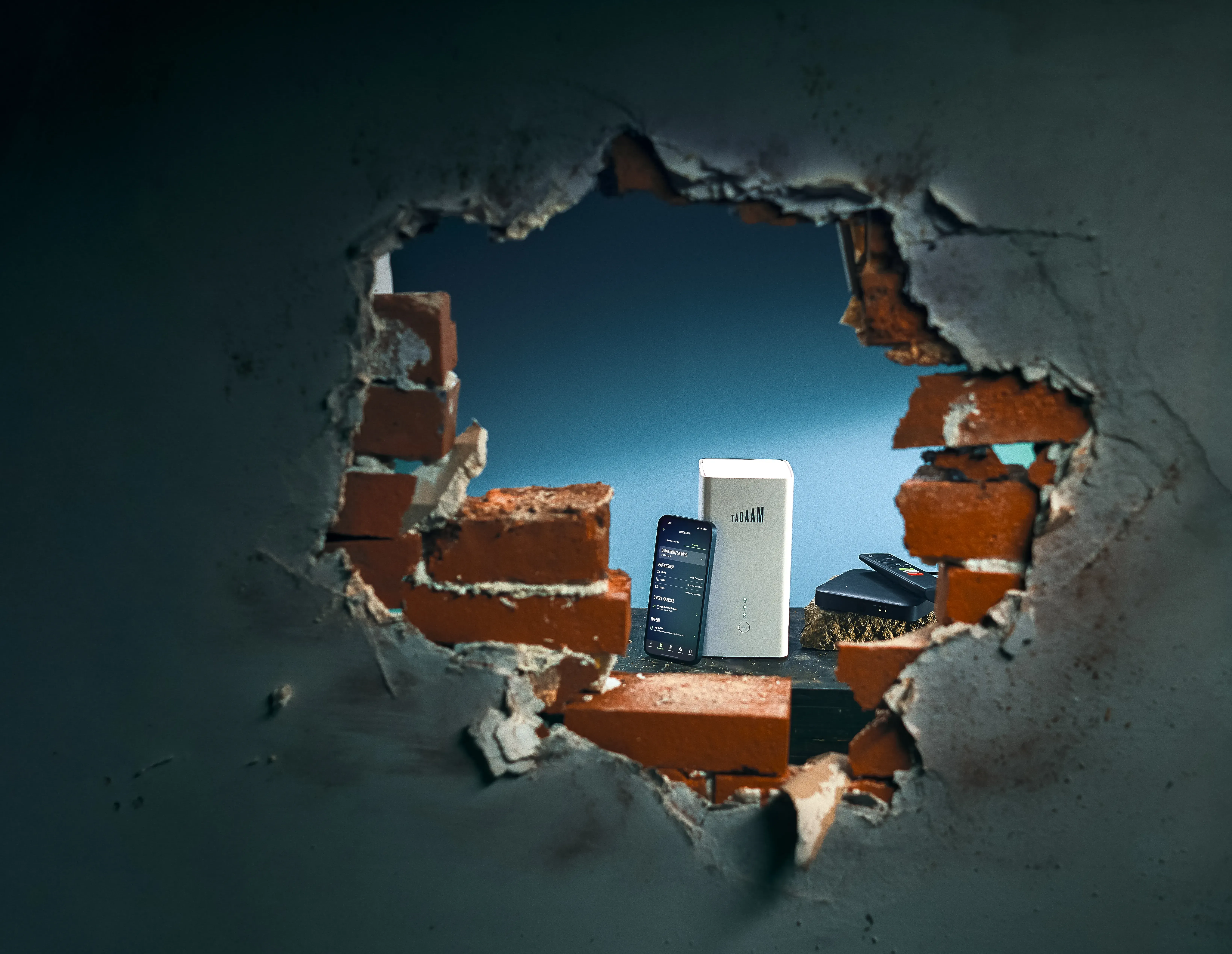 Modem en telefoon zichtbaar door een kapotte muur.