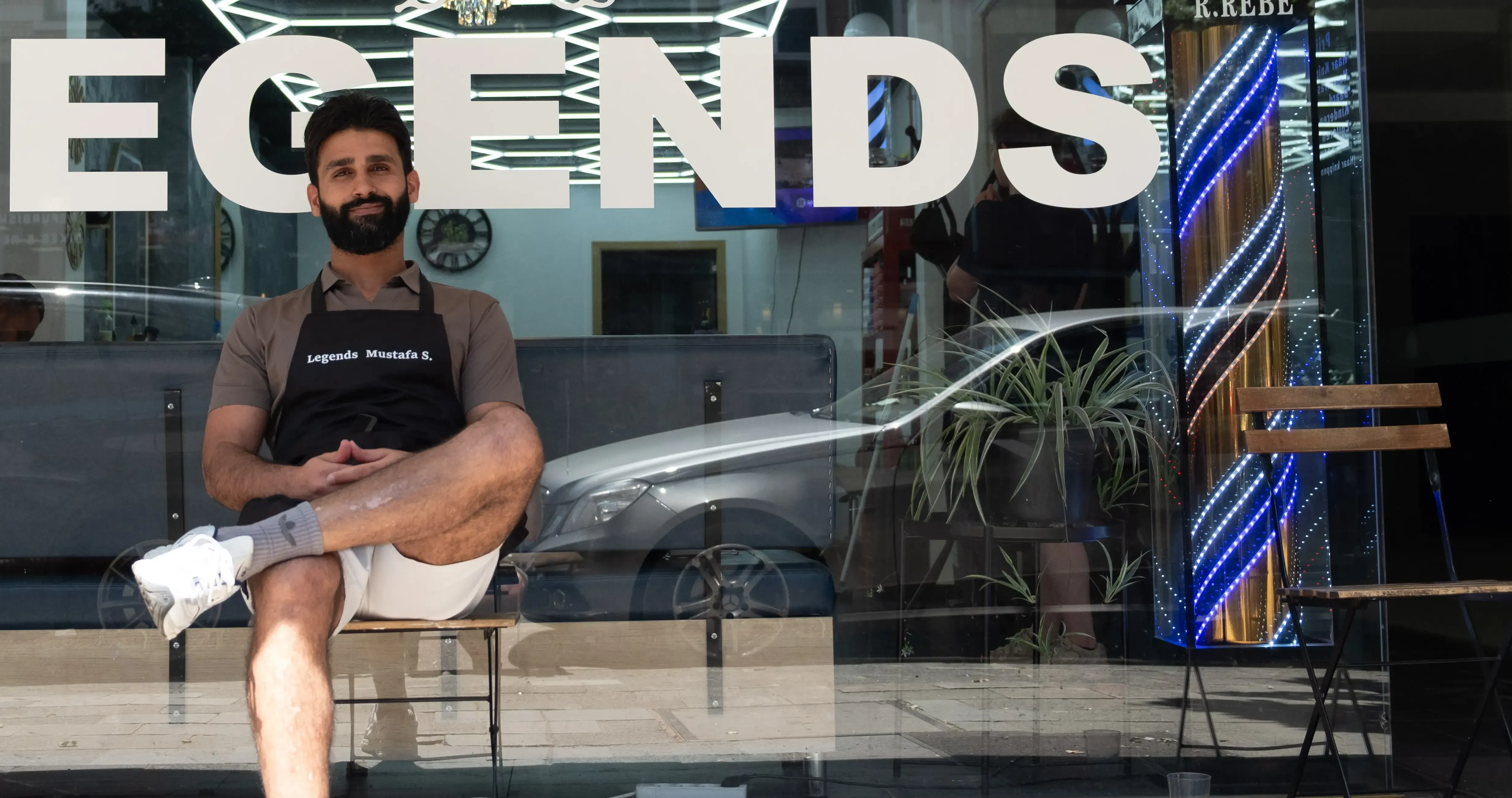 Man sitting in front of a barbershop.