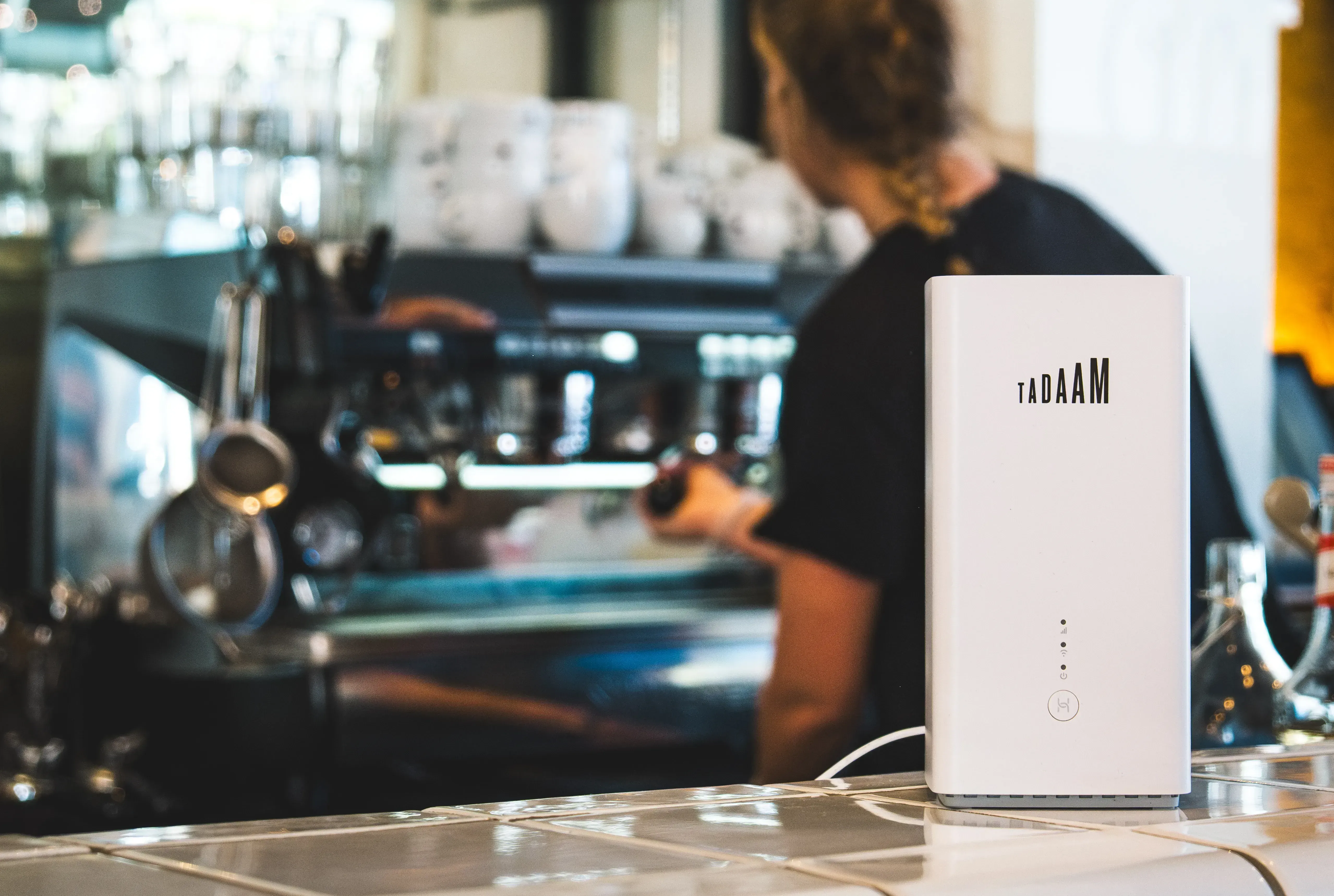 Barista making a coffee, TADAAM modem in front on the counter
