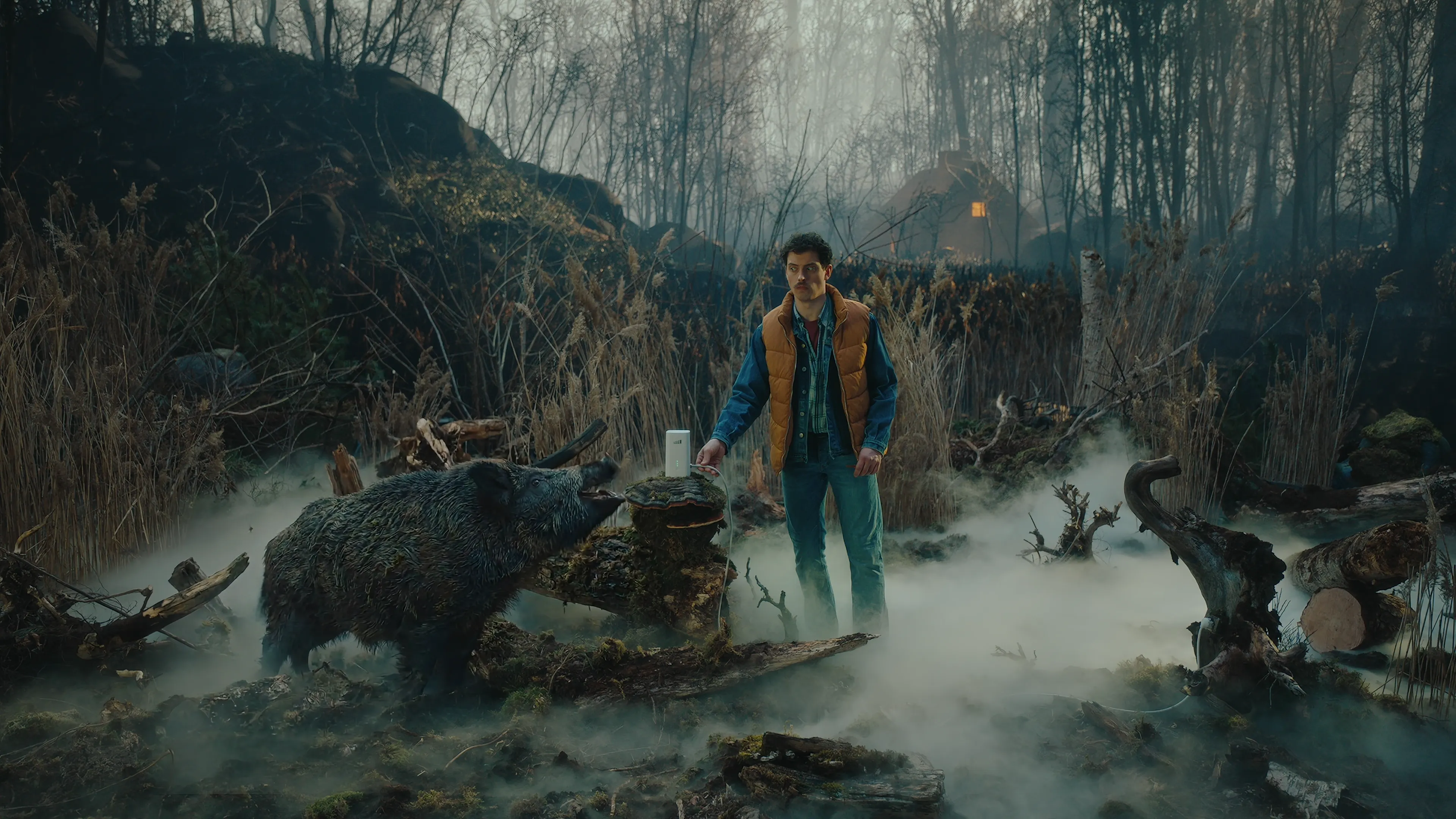 The image shows the main actor with a TADAAM-modem, standing in a forested area in the Ardennes with a boar nearby