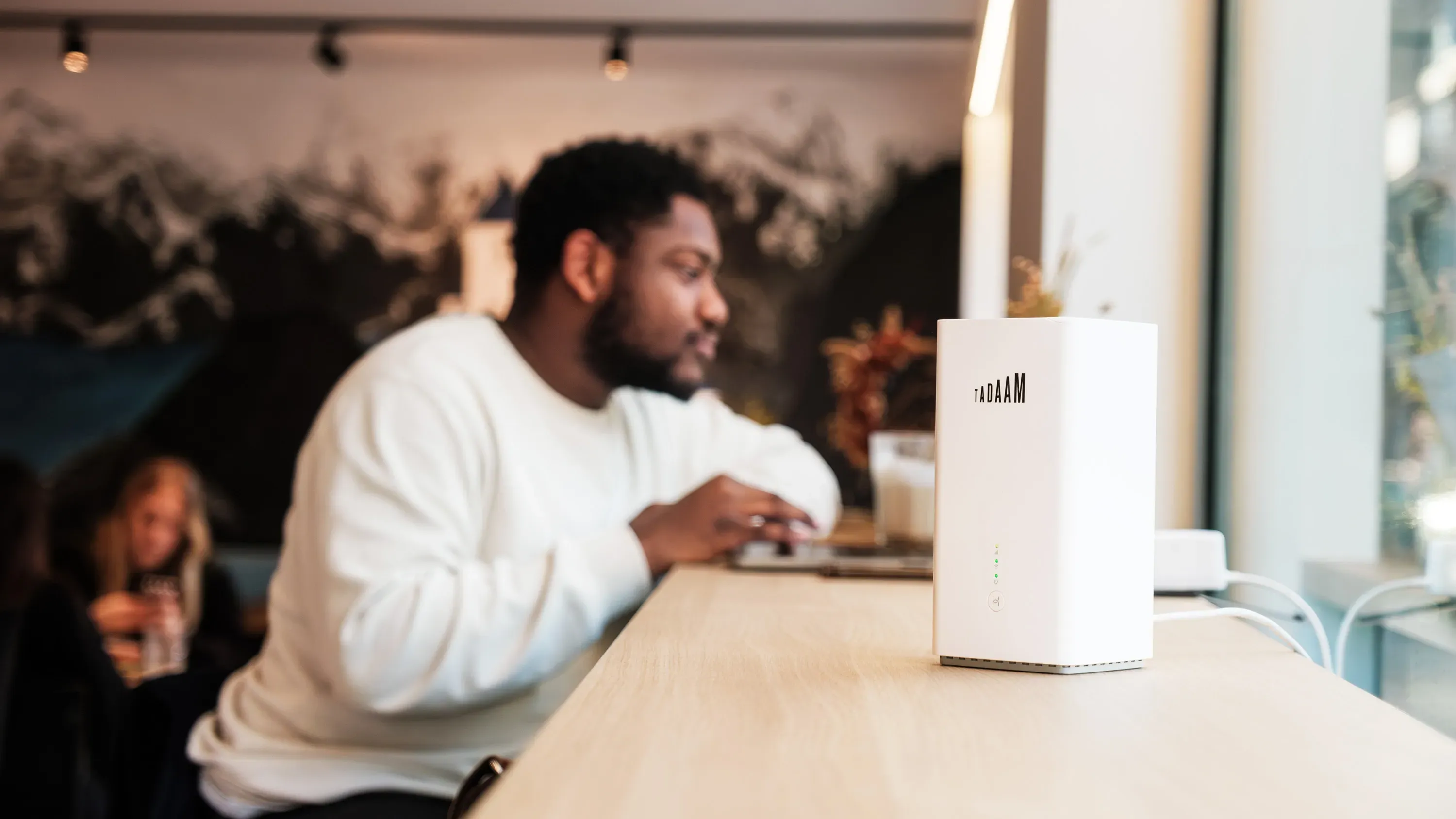 An image of a man working on a laptop with a TADAAM modem next to him.